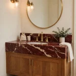 Elegant bathroom with a deep red marble vanity top, brass taps and warm wood cabinet