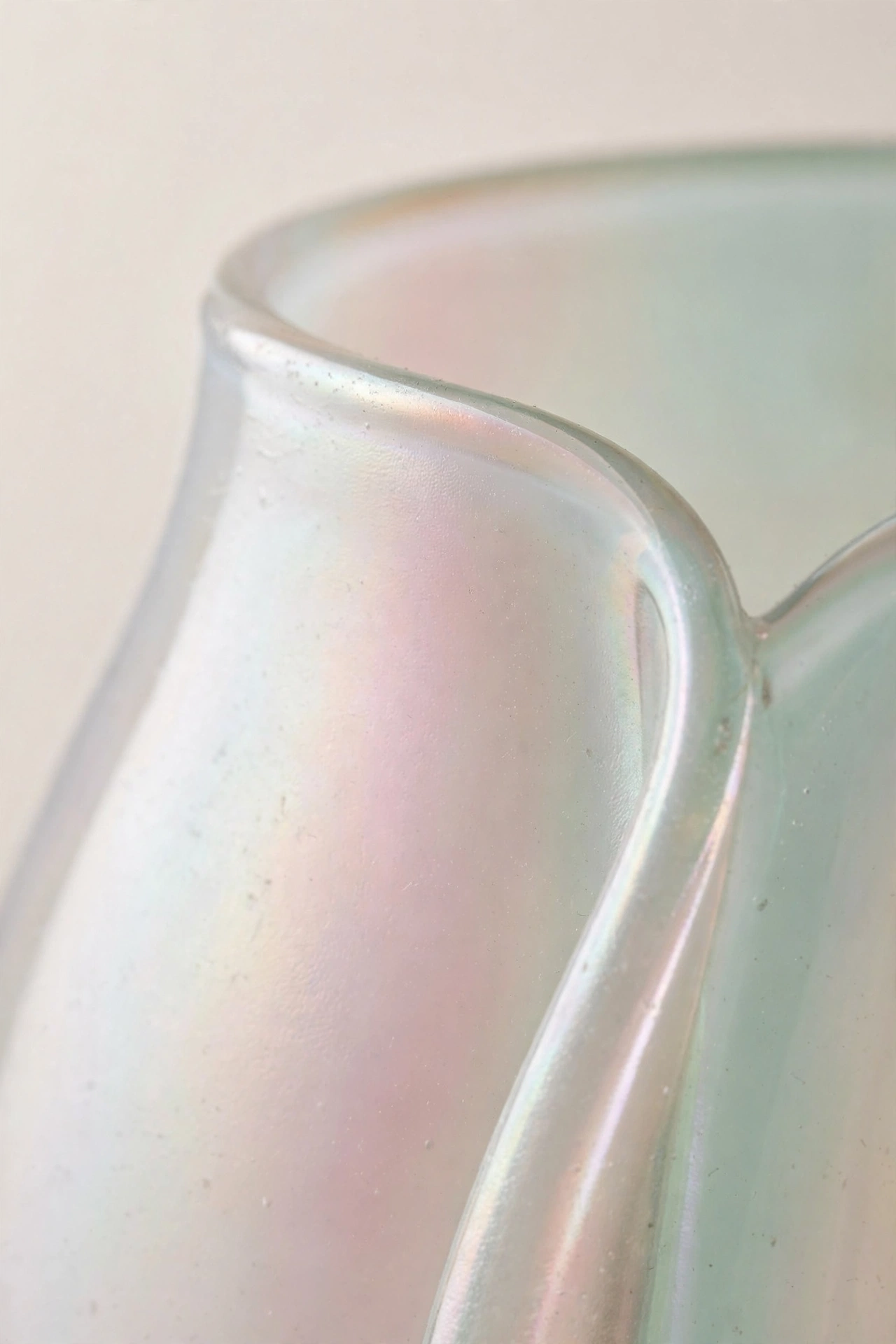 Close-up of an iridescent glass edge shifting from pearl to blush