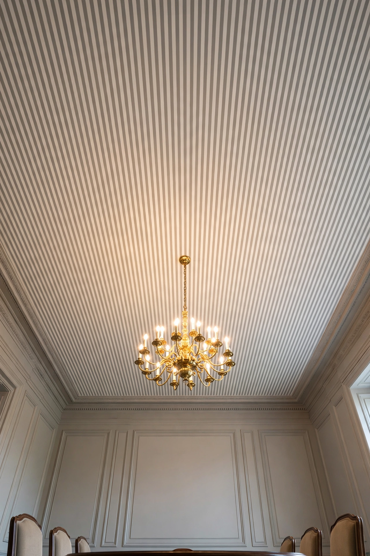 Narrow ivory and stone-grey stripes with a brass chandelier for a tailored dining room.